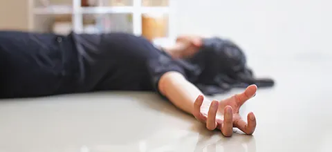 child lying motionless on the floor with one arm outstretched, as after a seizure